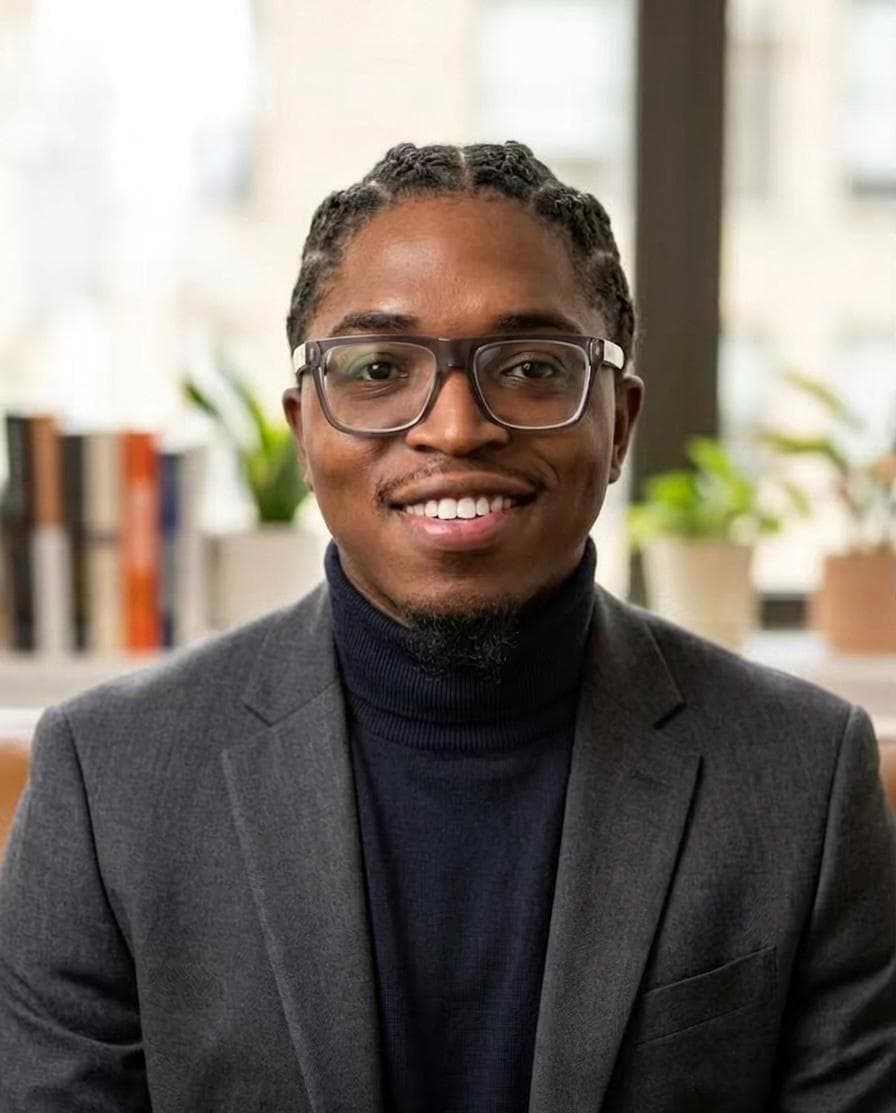 John Alante Richards smiling in a dark blazer and turtleneck.
